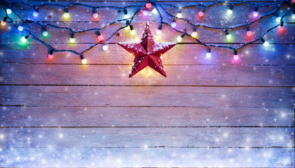 Wall Mural - christmas lights and star hanging on snowy plank