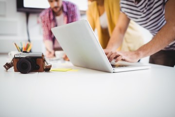 Wall Mural - Close-up of camera on desk with professionals working at office