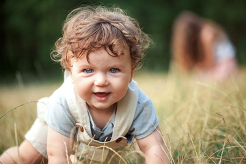 the little baby or year-old child on the grass in sunny summer day.