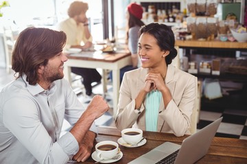 Poster - Smiling man and woman using a laptop while having cup of coffee