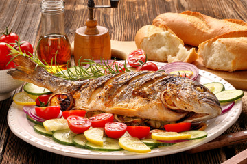 Grilled fish with baguette and vegetables on the plate