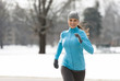 © Eric Hood - Smiling young woman running through Denver City Park in winter with snowy background