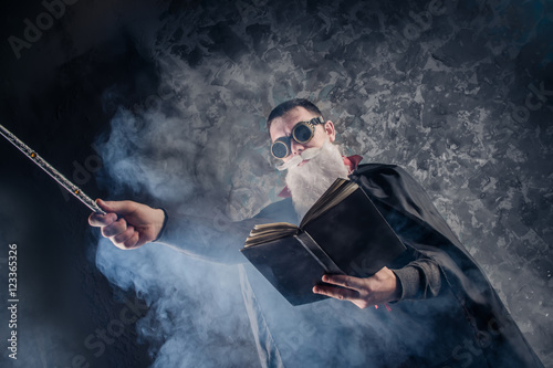 Fotomural evil wizard Merlin conjures and casts a spell, raising his wand, a young man dre