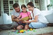 © WavebreakMediaMicro - Parents and daughter reading a book