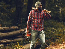 Lumberjack Worker Standing  In The Forest With Axe And Chainsaw