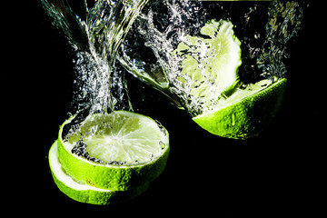 Wall Mural - Lemon slices splashing into water.