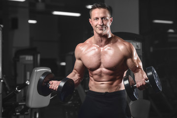 Handsome athletic fitness man posing and trains in the gym.