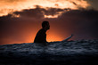 Surfer on the Beach at Sunrise or Sunset looking out to the ocean with reflection
