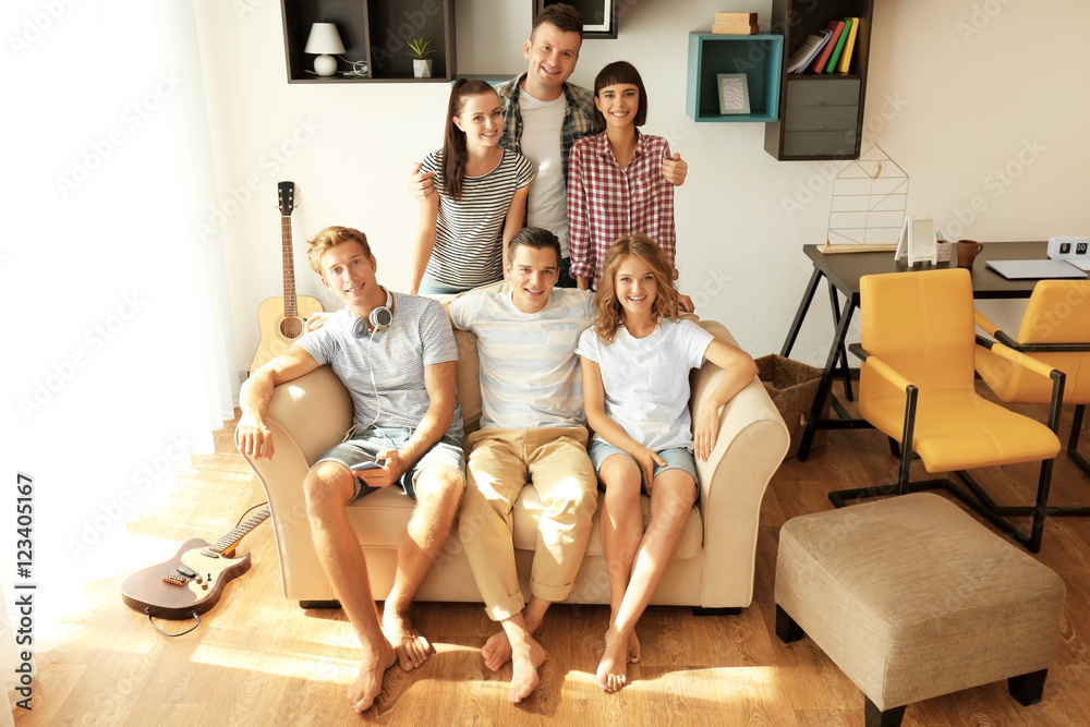 Happy friends sitting on couch at home