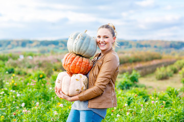 beautiful woman with three huge pumpkins on farm