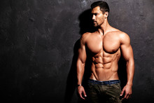 Portrait Of Strong Healthy Handsome Athletic Man Fitness Model Posing Near Dark Gray Wall