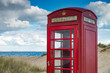 Battered British telephone box on a sandy beach