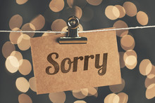 Sorry Sign Pegged To A String With Blurred Bokeh Lights In The Background