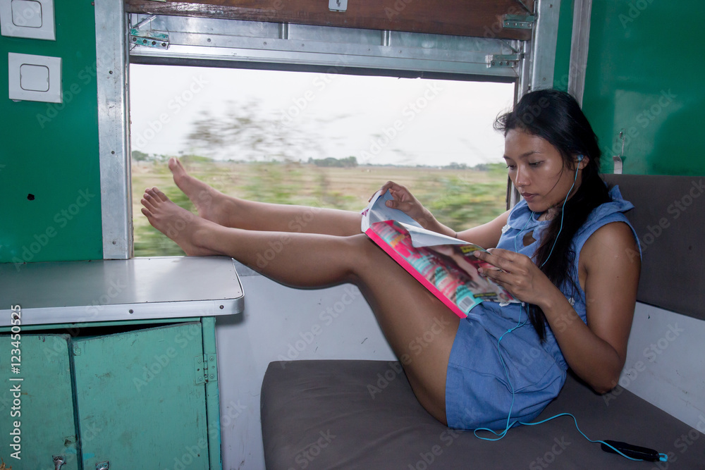 Asian girl sitting in a train with her legs on window, Myanmar (Burma