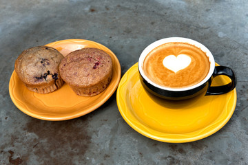 Art milk mocha coffee with foam and muffin on metal table