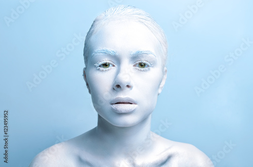 Fotografie, Obraz young woman with white make-up with white skin in the studio looking into the ca
