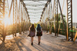 © ADDICTIVE STOCK - Two girls walking away on a bridge.