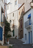Fototapeta Perspektywa 3d - narrow street with white houses in historical center of Cadaques, spain