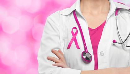 Sticker - Female doctor with pink ribbon on chest against color background. Oncology and breast cancer concept.