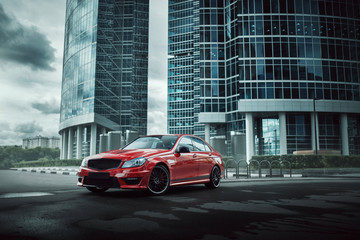 Wall Mural - Red car stay on asphalt road in the city at daytime