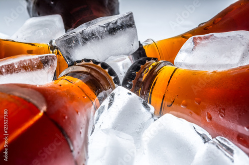 Fotografía Soda glass bottles in a refrigerated ice cubes on a light background