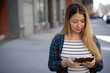 © blvdone - Young woman in city using tablet computer