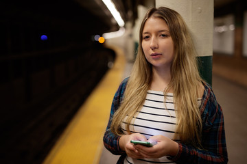 Poster - Young woman in city on subway platform texting cell phone