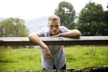 Portrait Of Man Leaning On Wooden Fence In Farm