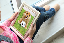 Little Girl Holding Photo Frame With Picture Of Dog. Happy Memories Concept.