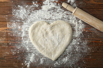 Wall Mural - Pizza dough in heart shape with flour on table