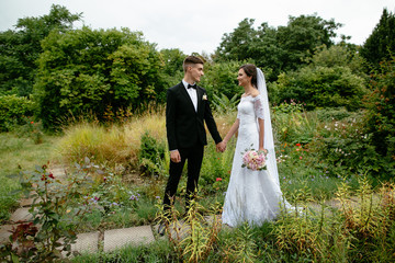 Wall Mural - Wedding. Beautifull bride and groom walking after wedding ceremony and holding hands.