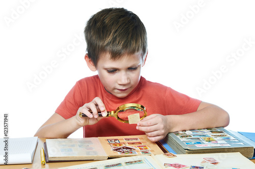 Fotografía Boy with magnifier looks his stamp collection isolated