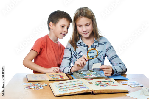 Fotomural Teen girl and little boy with magnifier looking his stamp collection isolated