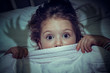 © Myst - cute little girl with scary eyes under the blanket in her bed