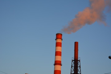 smoke from the striped tube heat and power plant against the blue sky, heat, pollution, urban landscape