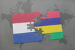 puzzle with the national flag of netherlands and mauritius on a world map background.