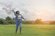 © sunti - A beautiful young woman holding balloons , running along the pas