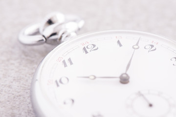 Pocket watch in close up lying on stone table. Vintage timepiece still life. Concept of time, deadline and nostalgia.