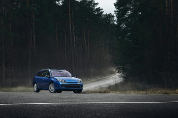 Blue car standing on asphalt road at daytime