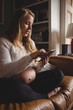 © Wavebreak Media - Pregnant woman using mobile phone in living room
