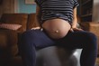© Wavebreak Media - Midsection of pregnant woman sitting on exercise ball in living room