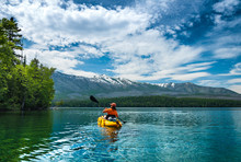 Kayaking In The Spring By Snow Covered Mountains On Lake McDonald In Glacier National Park Montana