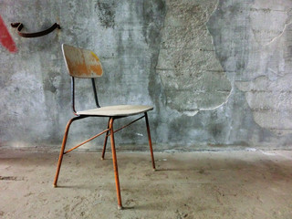 Old chair lonely resting in front of concrete wall