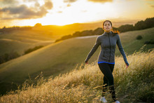 Young Woman Enjoys A Walk Through The Countryside At Sunset.