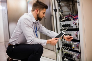 Fototapete - Technician using digital tablet while analyzing server
