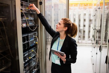 Fototapete - Technician holding digital tablet while examining server