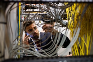 Fototapete - Technician talking on mobile phone while checking cables