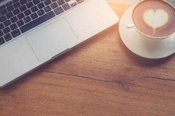 Poster - Laptop and coffee cup on wooden table with vintage filter