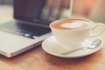 Poster - Laptop and coffee cup on wooden table with vintage filter