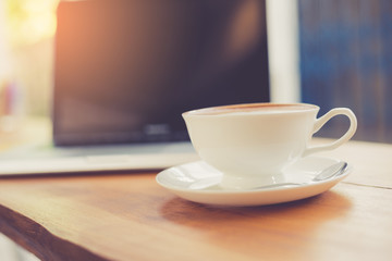 Poster - Laptop and coffee cup on wooden table with vintage filter
